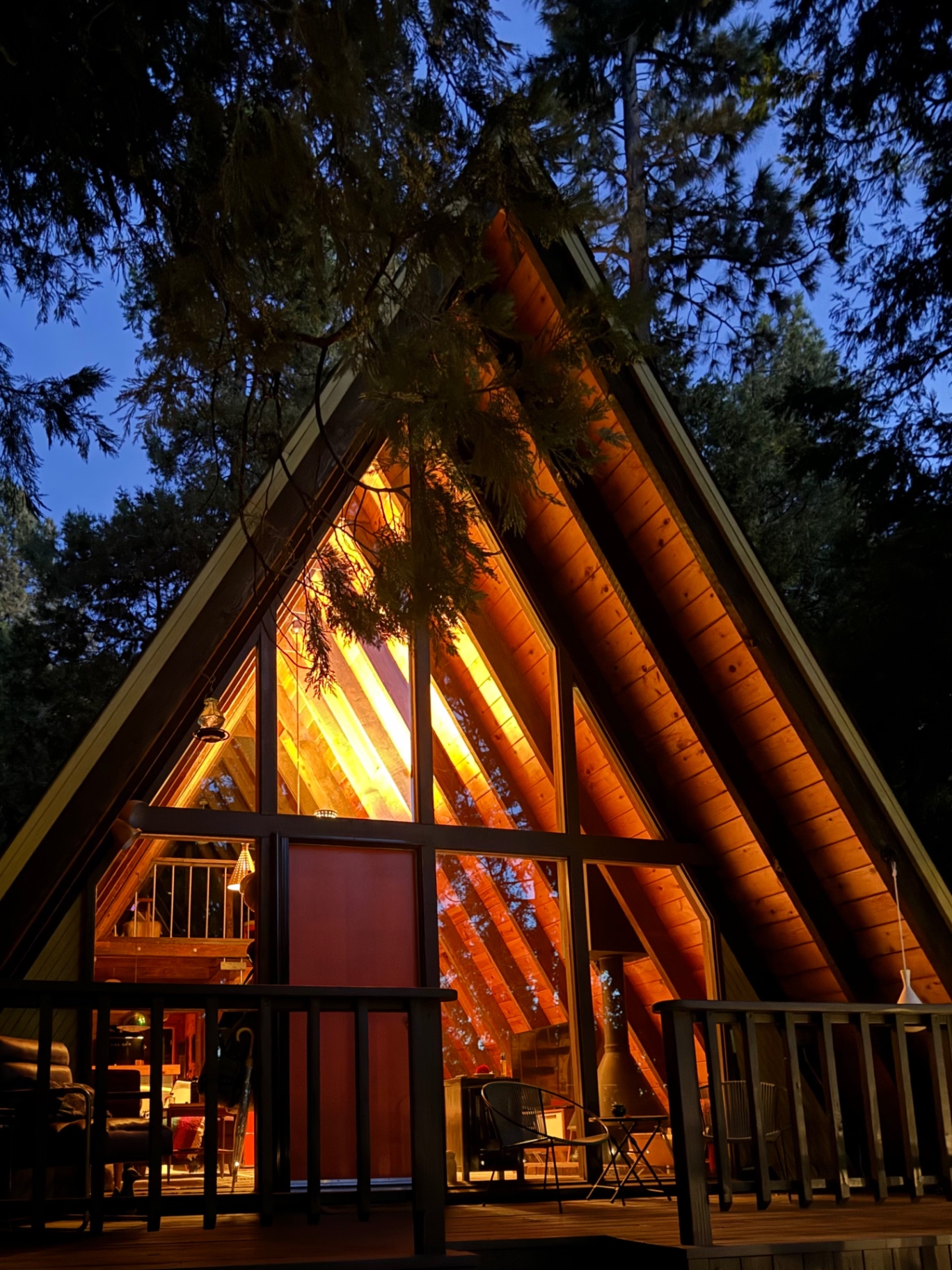 House Little Bird A-Frame glowing at dusk through the pines